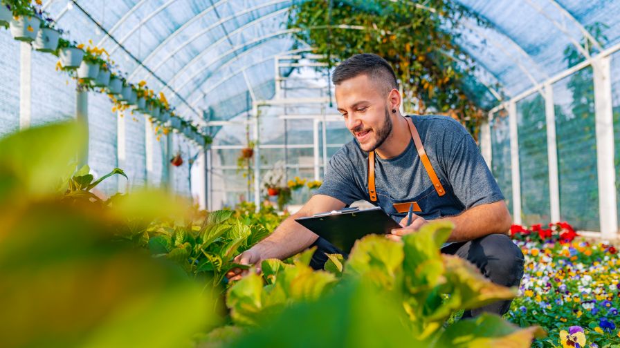 Shot of a happy male florist in his garden center managing crops and performing cost-benefit analysis on production