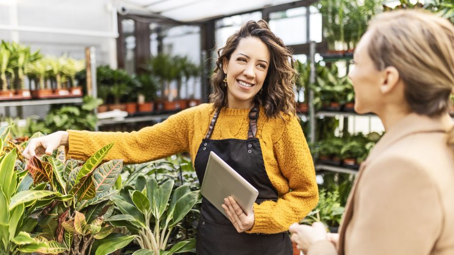 Smiling woman at a garden center talking with an employee for help buying plants