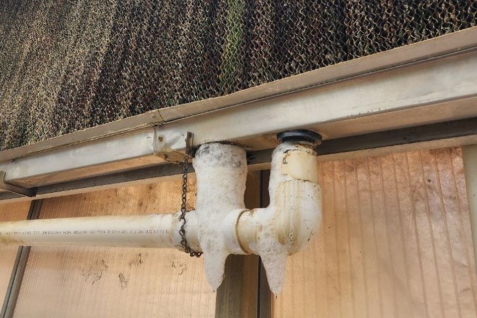 Water is leaking out of the return pipe from this pad-and-fan system, not only reducing efficiency but creating a puddle below in a busy walkway.