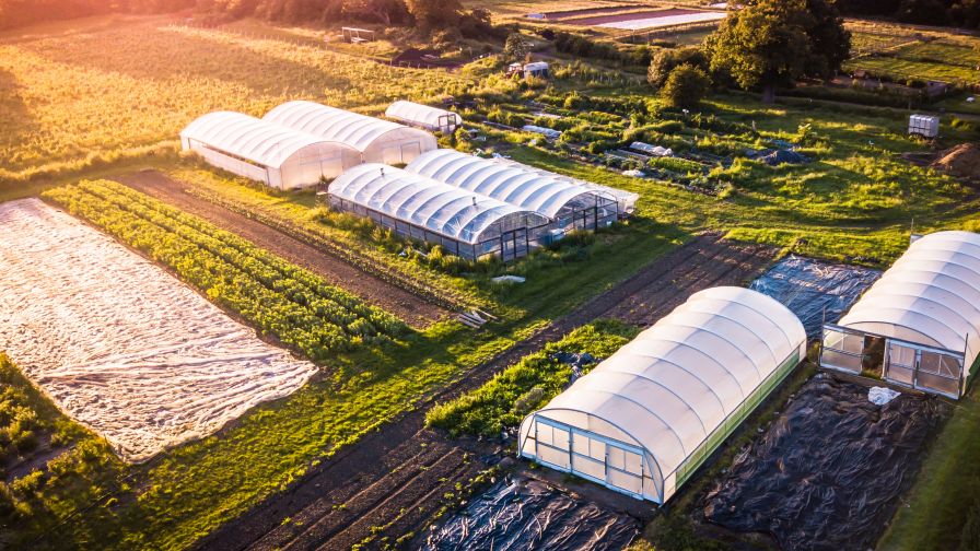 Drone aerial photography of an organic inner city farm taken at sun set in London. Polytunnels, agricultural buildings and farmland taken on the outskirts of a city.
