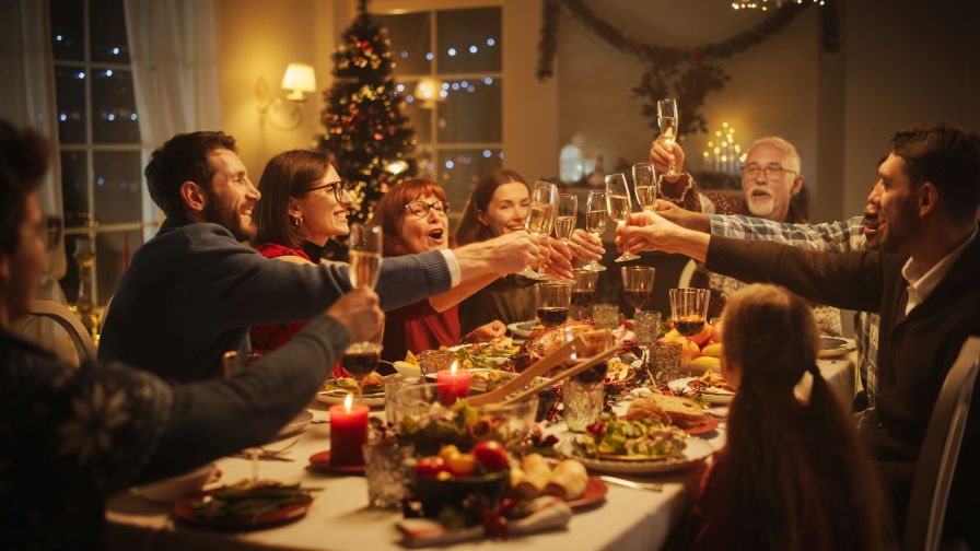 Big diverse family celebrating the holiday at dinner table with raised glasses.